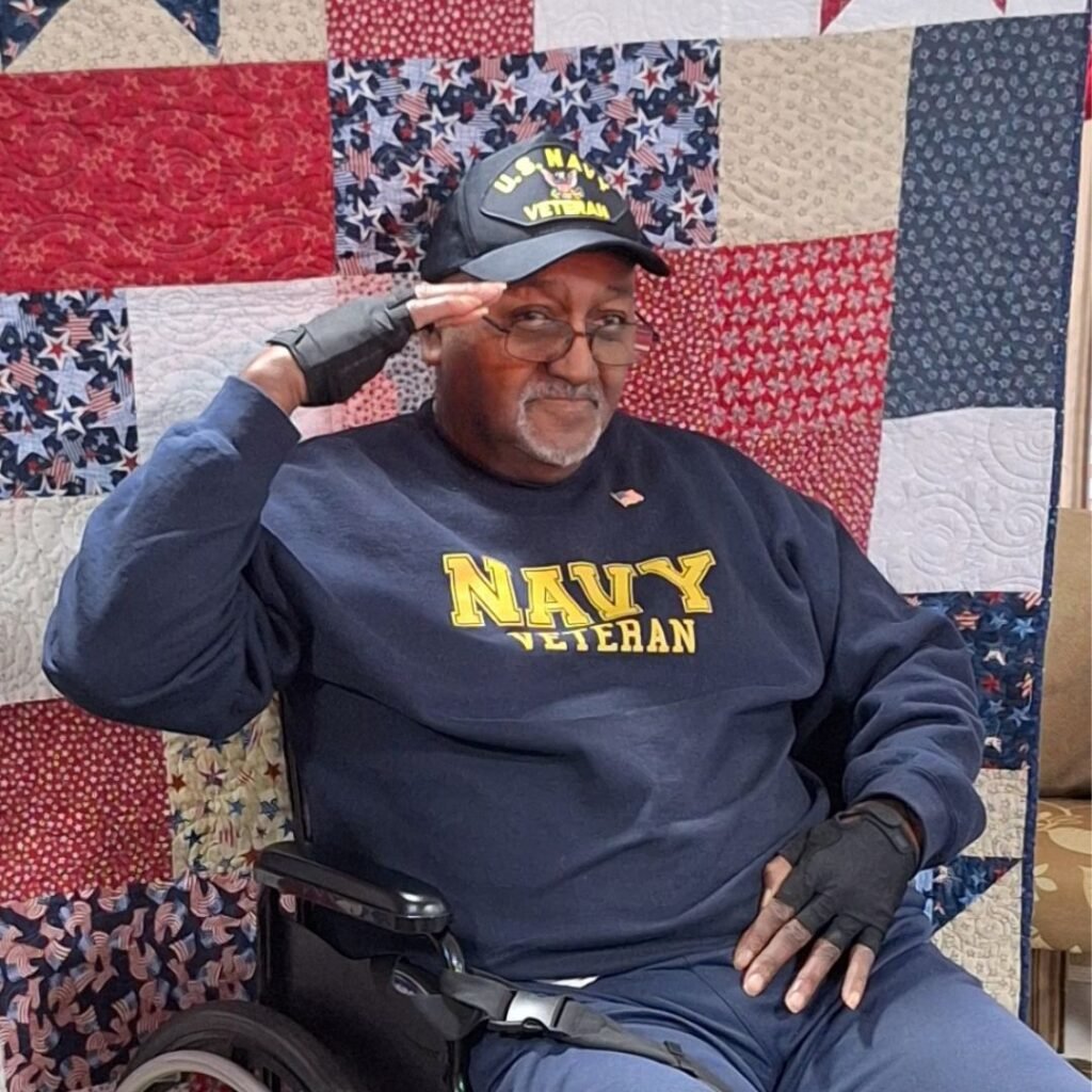 Veteran resident saluting in front of freedom quilt