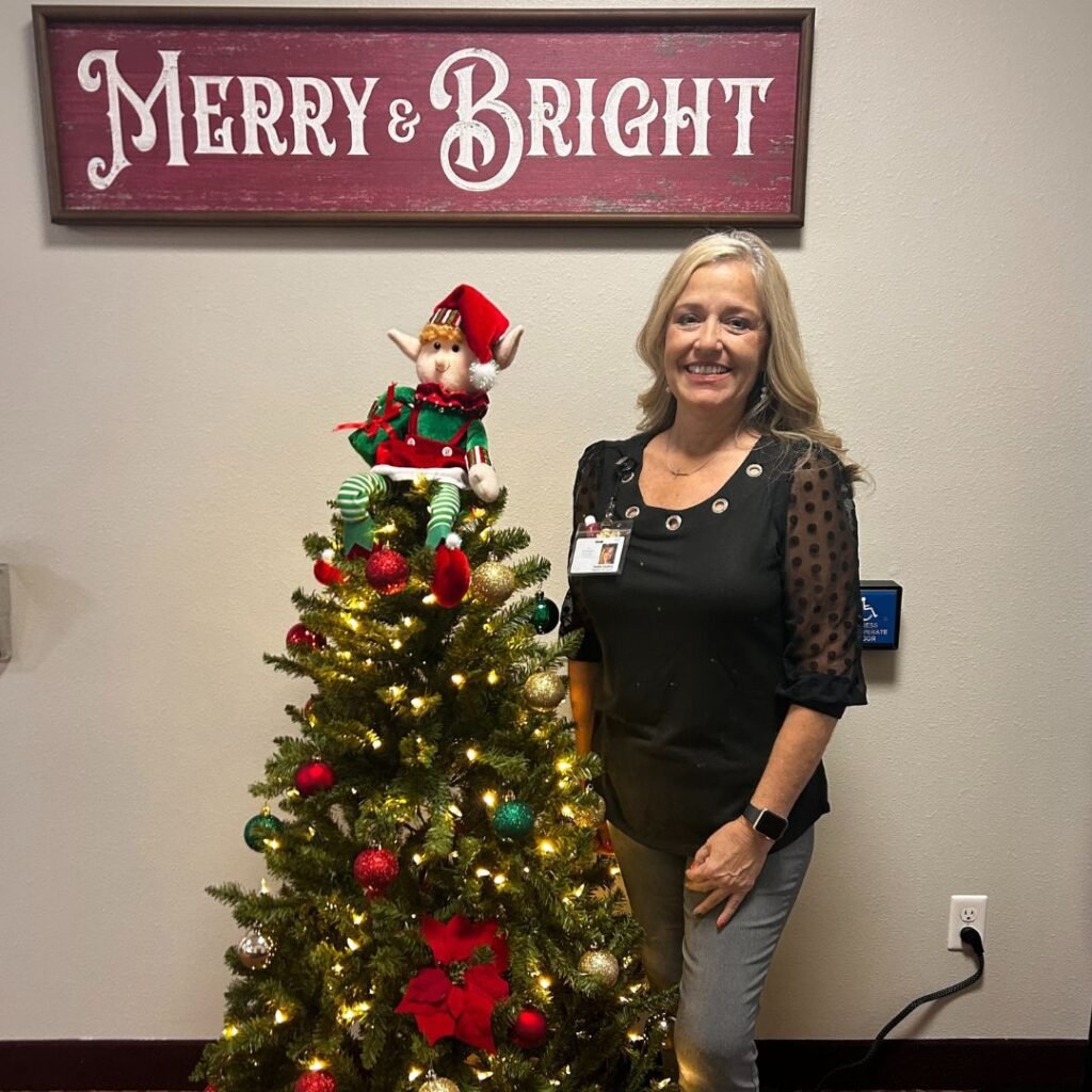Activities Director posing in front of Dayton's giving tree