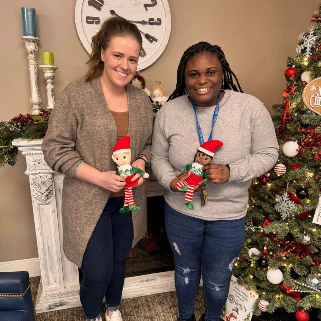 Team members pose with their elf doll gifts