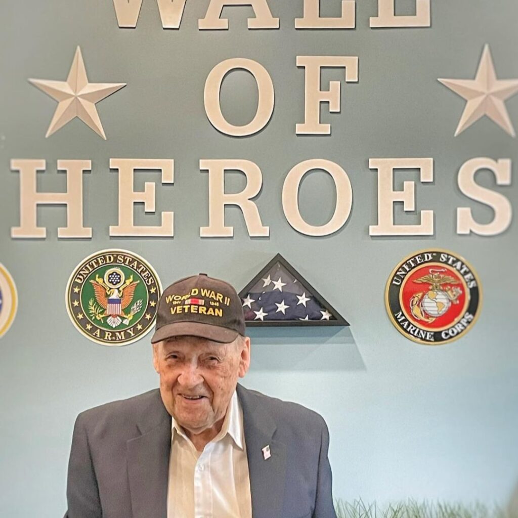 Resident poses in front of Wall of Honor