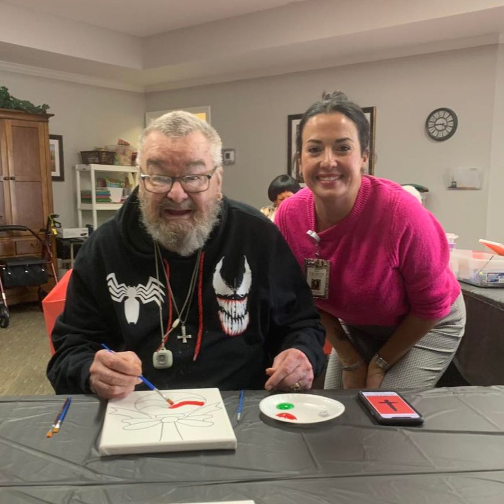 Resident and team member participate in fun Christmas painting activity