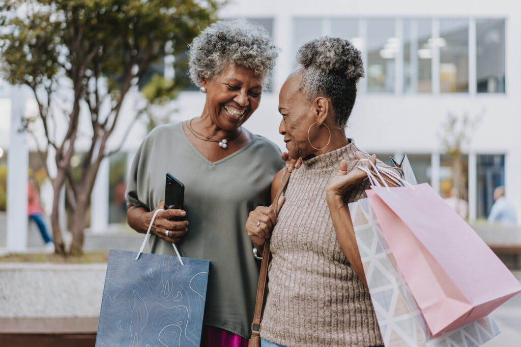 Two senior friends shopping at the mall holding bags