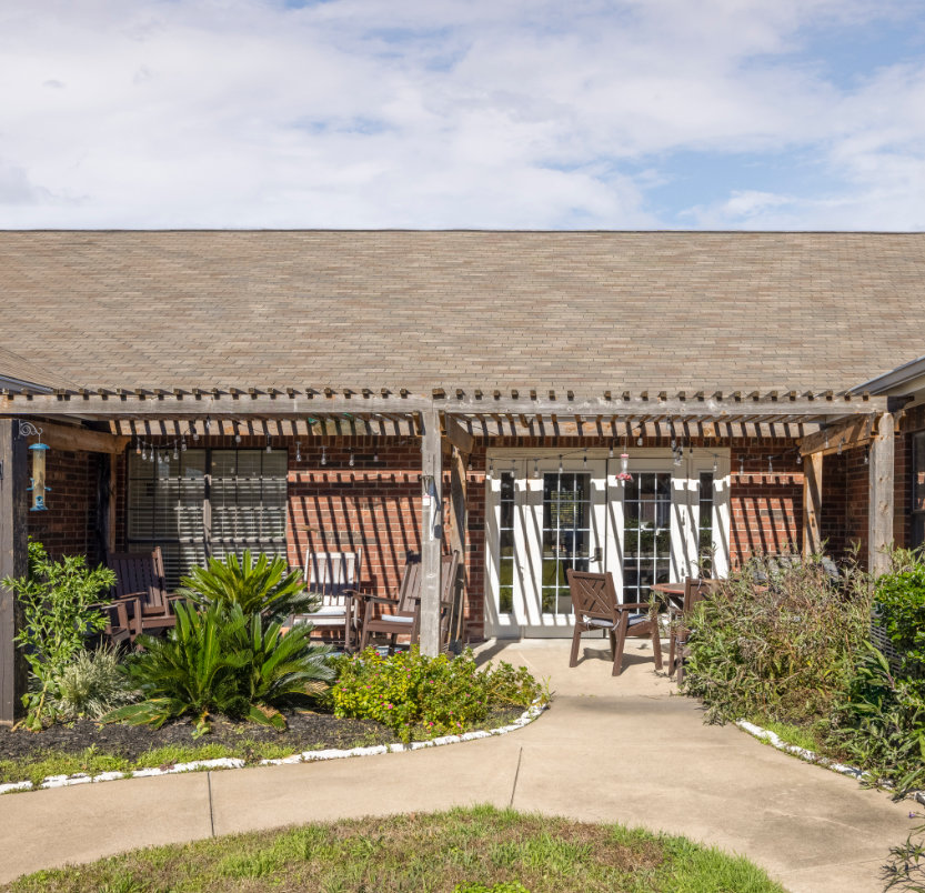 Outside courtyard with seating and a walking path at a senior living community in College Station, Texas