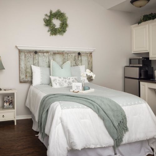 Senior living bedroom with full size bed and kitchenette at the Waterford at College Station senior living community in College Station, Texas