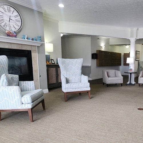 Lobby area in a senior living community with comfortable chairs near a fireplace