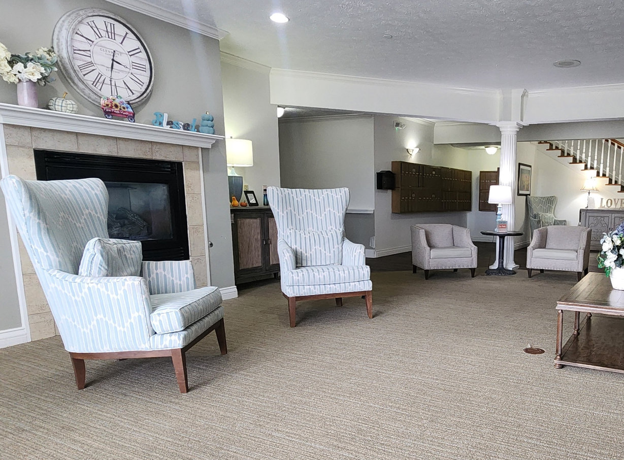 Lobby area in a senior living community with comfortable chairs near a fireplace