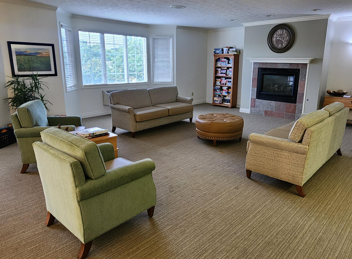 Comfortable lounge with chairs, couches, a game shelf and a fireplace