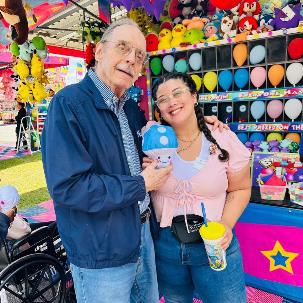 Team member and resident pose with carnival game prize