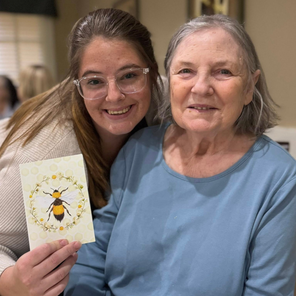 Receptionist posing with resident and handmade card