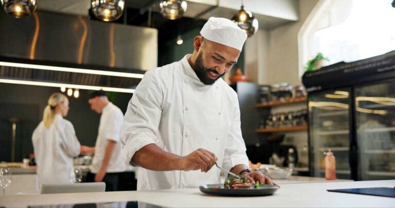 Chef happily plating an entree in kitchen