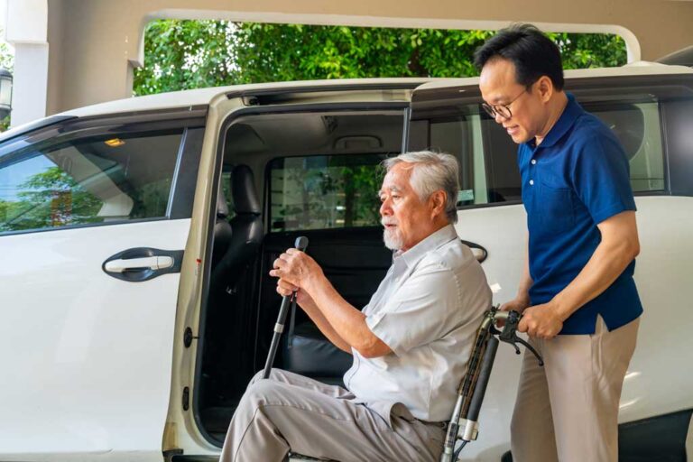 Elderly man with wheelchair being assisted into shuttle van