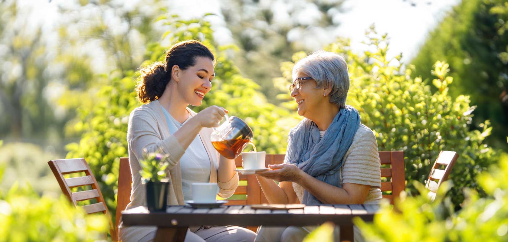 Younger woman serves tea to her elderly mother