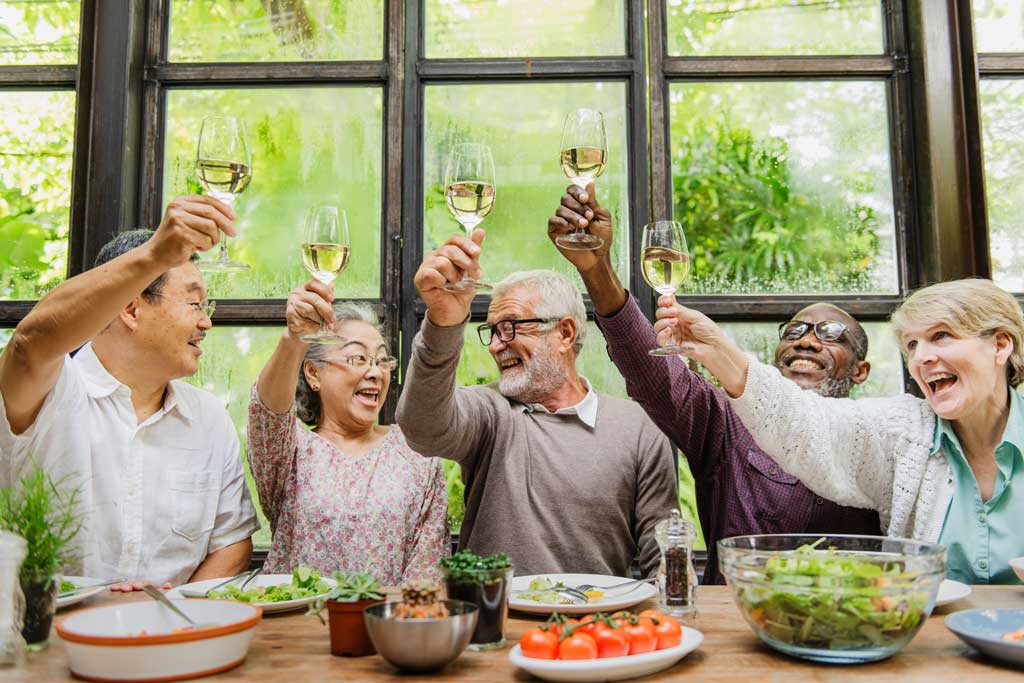 Diverse group of seniors enjoying dinner and toasting