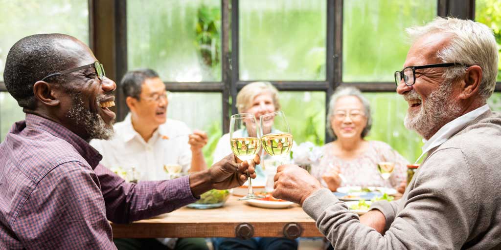 Diverse group of seniors enjoying dinner and toasting