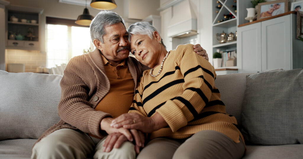 stock senior man and senior woman hold hands on couch